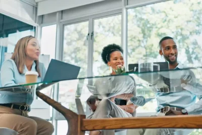 3 people sat at a boardroom table smiling